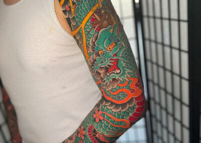 tattoo of green dragon with red belly and flames full sleeve