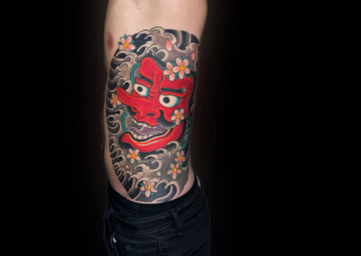 Japanese Traditional tattoo of mask in water with cherry blossoms on rib cage