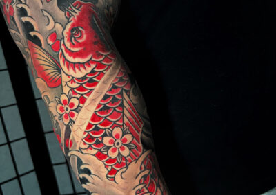 Japanese Traditional tattoo of red koi with water and rocks background full sleeve