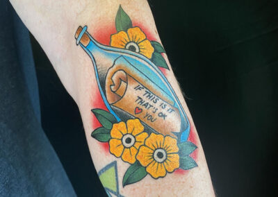 American traditional tattoo of message in a bottle with flowers