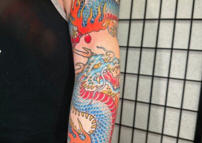 Japanese traditional blue dragon with red belly tattoo wrapped around arm