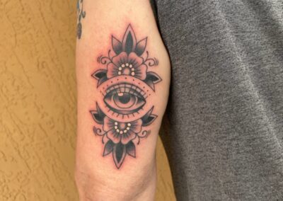 black gray eye with flowers on arm tattoo