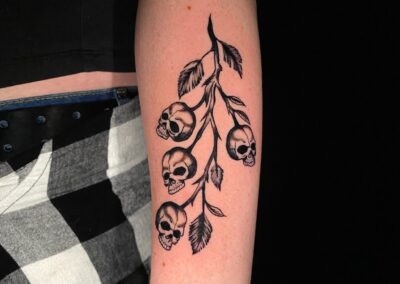 black and gray skulls on a branch tattoo
