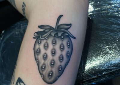 black and gray strawberry with eyes tattoo