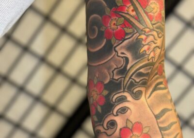 Japanese traditional sleeve with waves, rocks and red cherry blossoms tattoo